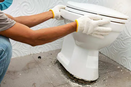 professional plumber repairing a toilet